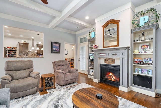 living area featuring dark wood finished floors, beamed ceiling, recessed lighting, coffered ceiling, and a glass covered fireplace