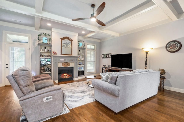 living area featuring beam ceiling, a wealth of natural light, a ceiling fan, and dark wood finished floors