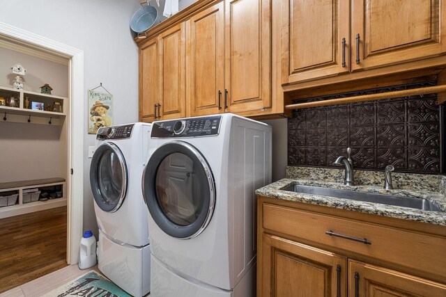 laundry area with a sink, independent washer and dryer, and cabinet space