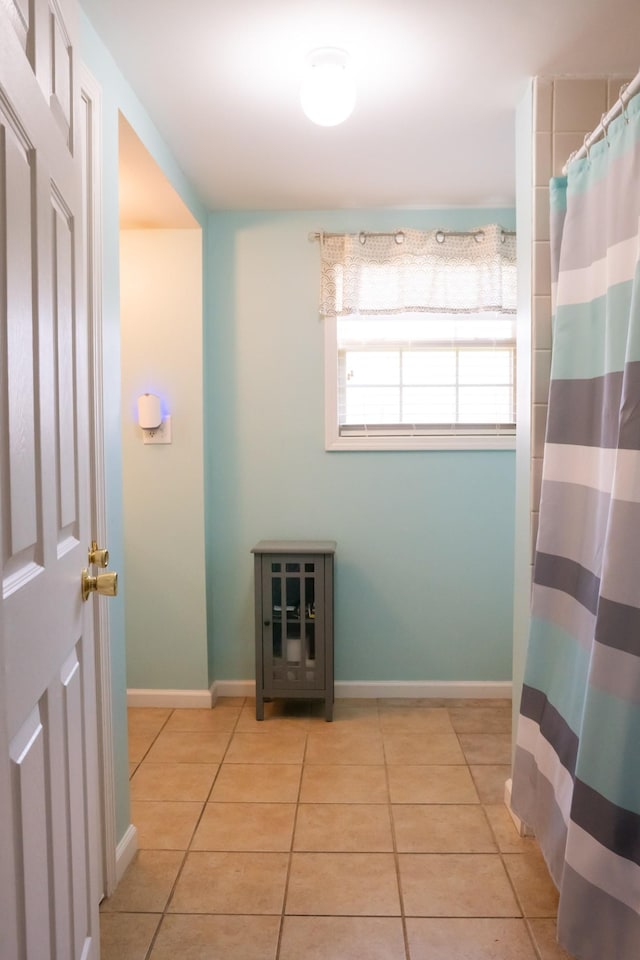 bathroom featuring a shower with curtain, baseboards, and tile patterned flooring