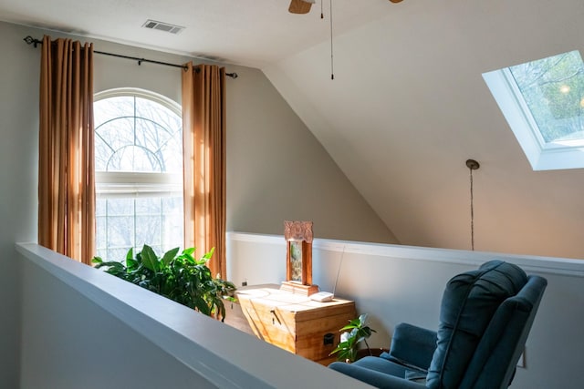 living area with visible vents, vaulted ceiling with skylight, plenty of natural light, and a ceiling fan