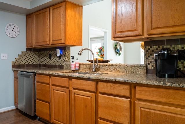 kitchen with stainless steel dishwasher, dark wood finished floors, light stone countertops, a sink, and decorative backsplash