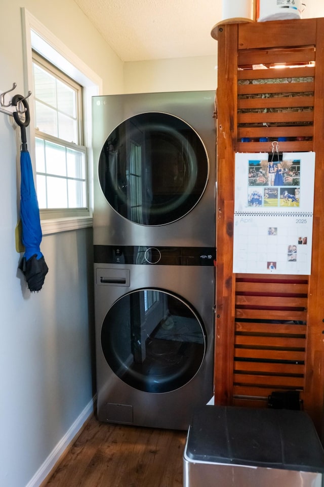 laundry room with laundry area, wood finished floors, baseboards, and stacked washer / drying machine