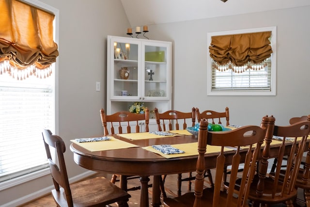 dining area featuring baseboards and lofted ceiling