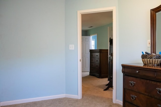 corridor featuring light colored carpet and baseboards