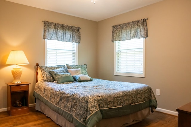 bedroom featuring wood finished floors, baseboards, and multiple windows