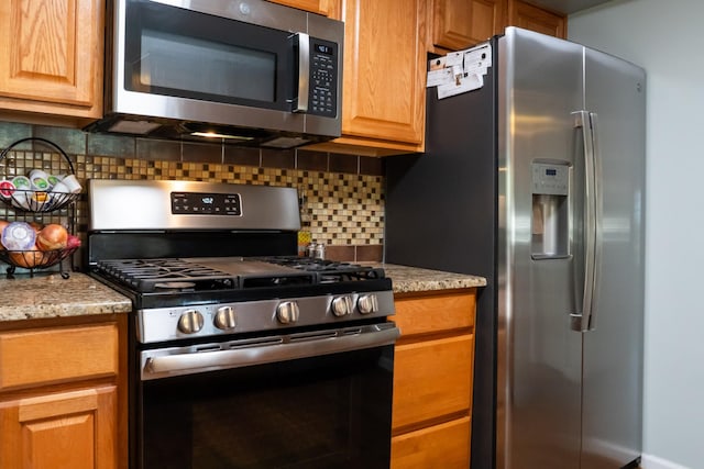 kitchen with stainless steel appliances, tasteful backsplash, and light stone counters