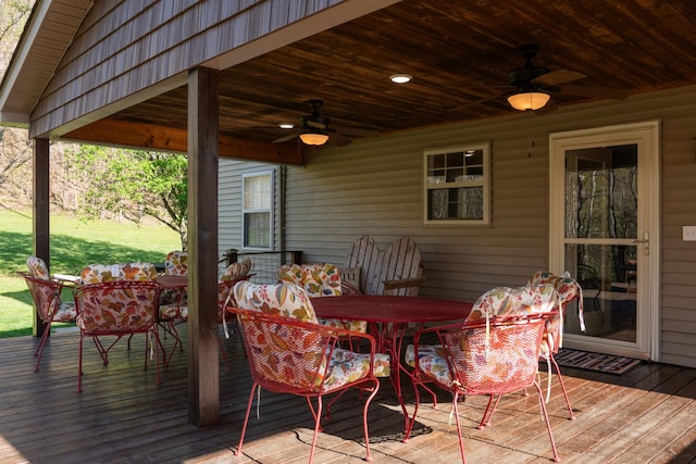 wooden deck with outdoor dining space and a ceiling fan