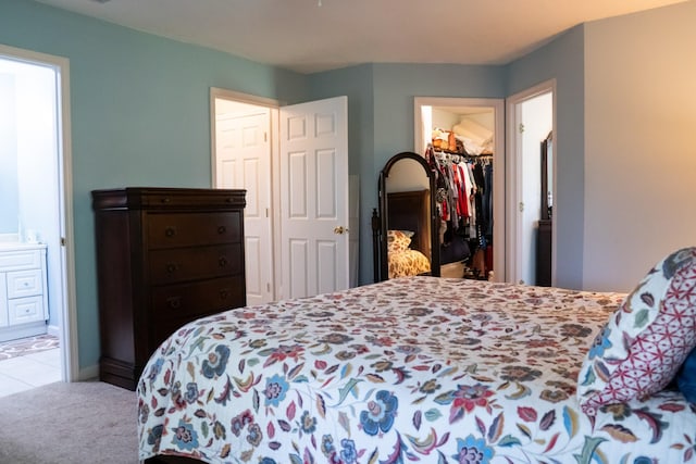 carpeted bedroom featuring tile patterned floors, a walk in closet, ensuite bath, and a closet