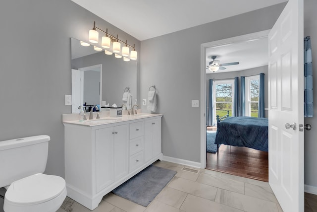 bathroom with toilet, double vanity, a sink, and connected bathroom