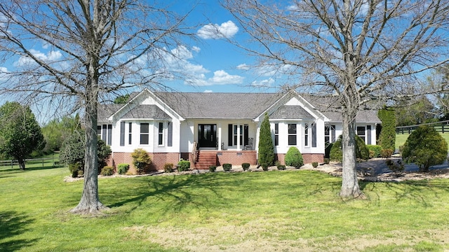 ranch-style home with brick siding, a front lawn, and a shingled roof