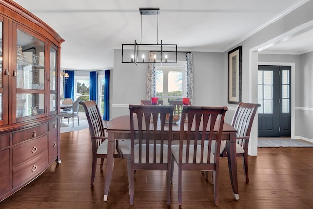 dining room with dark wood-style flooring, ornamental molding, baseboards, and a notable chandelier