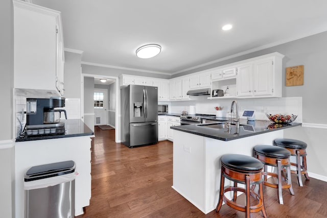kitchen featuring crown molding, backsplash, appliances with stainless steel finishes, and a peninsula