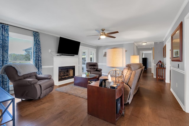 living area with ceiling fan, a fireplace with flush hearth, ornamental molding, baseboards, and dark wood-style floors