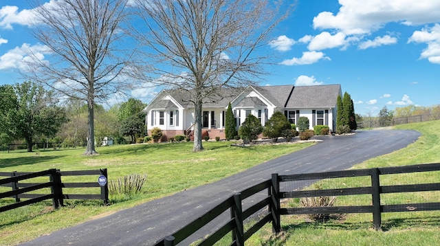 view of front of house with a front yard, fence, brick siding, and driveway