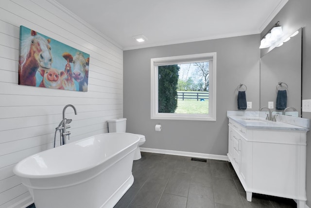 full bath with vanity, baseboards, wooden walls, crown molding, and a freestanding bath