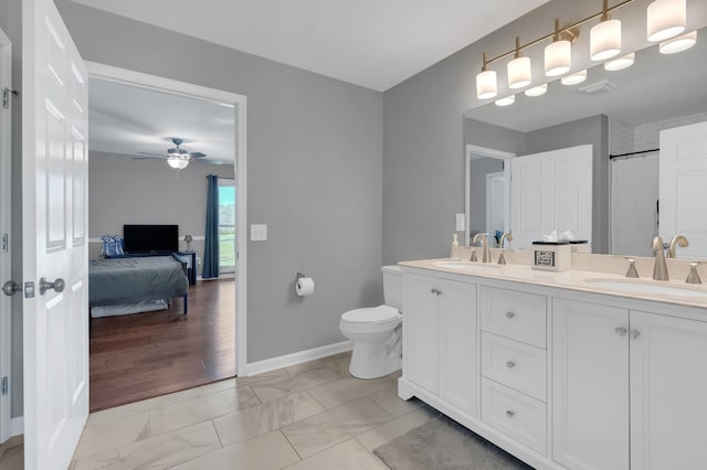 ensuite bathroom with marble finish floor, a sink, a ceiling fan, and baseboards