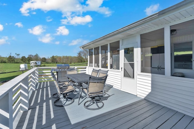 wooden deck with a sunroom, grilling area, and outdoor dining area