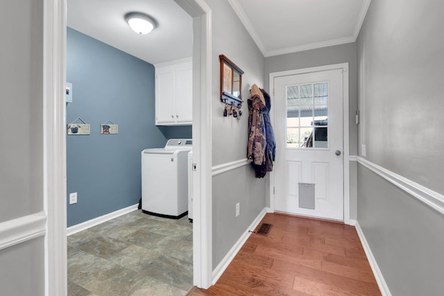 washroom featuring visible vents, baseboards, ornamental molding, cabinet space, and washing machine and dryer
