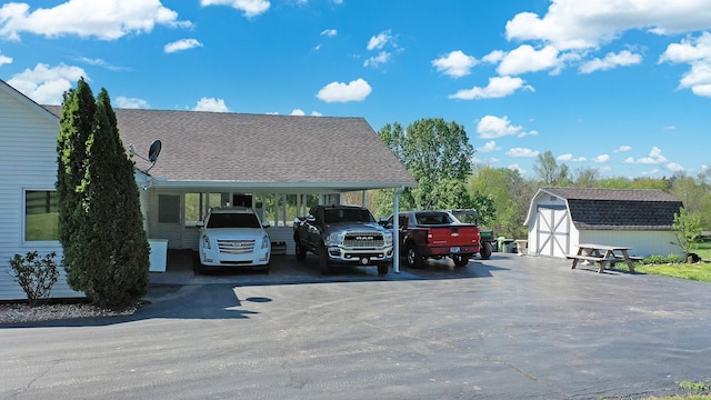view of vehicle parking with a shed, a carport, and driveway