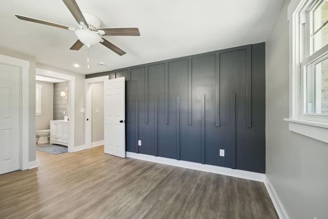 unfurnished bedroom featuring wood finished floors, baseboards, and multiple windows