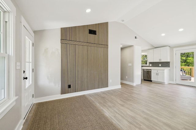 unfurnished living room with visible vents, baseboards, light wood finished floors, and lofted ceiling