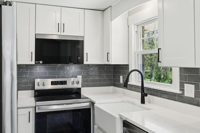 kitchen featuring light countertops, backsplash, white cabinets, appliances with stainless steel finishes, and a sink