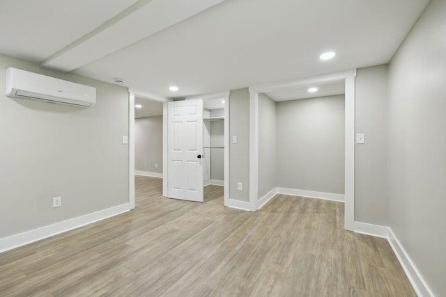 finished below grade area with recessed lighting, light wood-type flooring, an AC wall unit, and baseboards