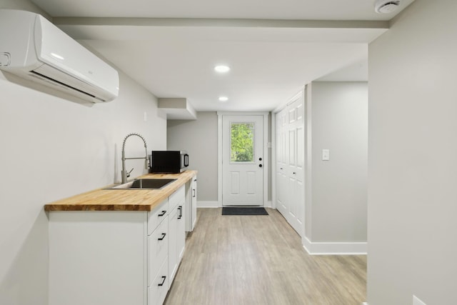 kitchen with light wood-style floors, butcher block counters, recessed lighting, a wall mounted AC, and a sink