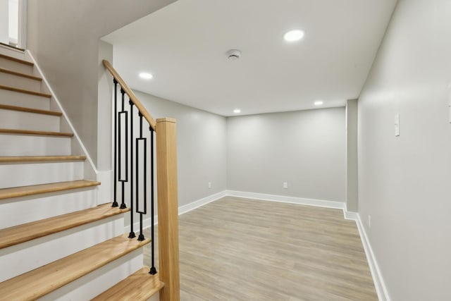 basement featuring recessed lighting, stairway, light wood-style floors, and baseboards