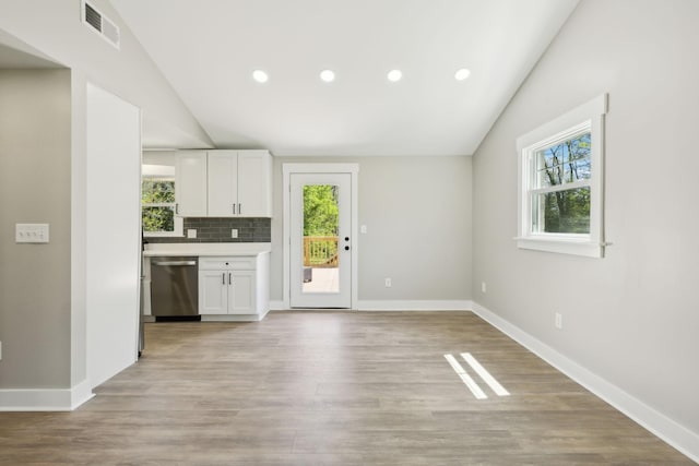 kitchen with stainless steel dishwasher, visible vents, vaulted ceiling, and a healthy amount of sunlight