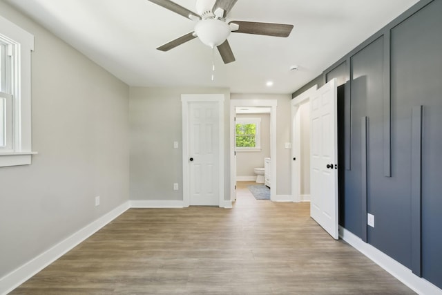 unfurnished bedroom with baseboards, light wood-type flooring, ensuite bath, and a ceiling fan
