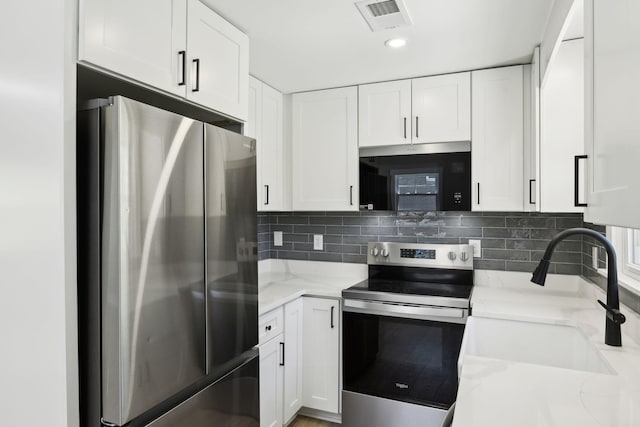 kitchen featuring visible vents, a sink, appliances with stainless steel finishes, white cabinetry, and light stone countertops