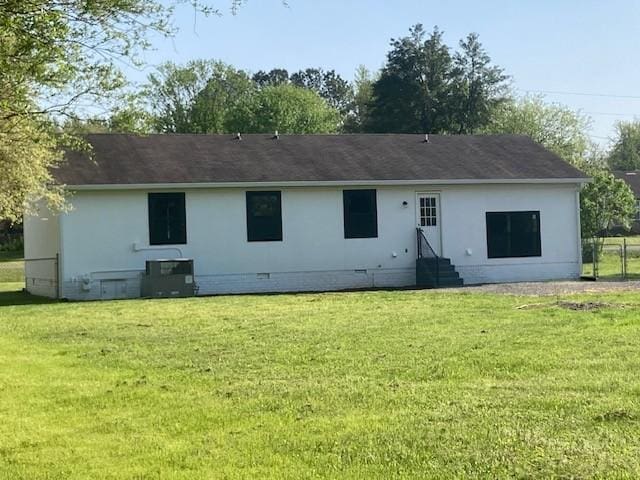 back of property featuring crawl space, entry steps, a yard, and stucco siding