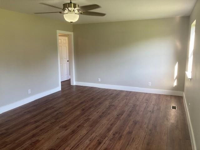 empty room featuring dark wood-type flooring, visible vents, baseboards, and a ceiling fan