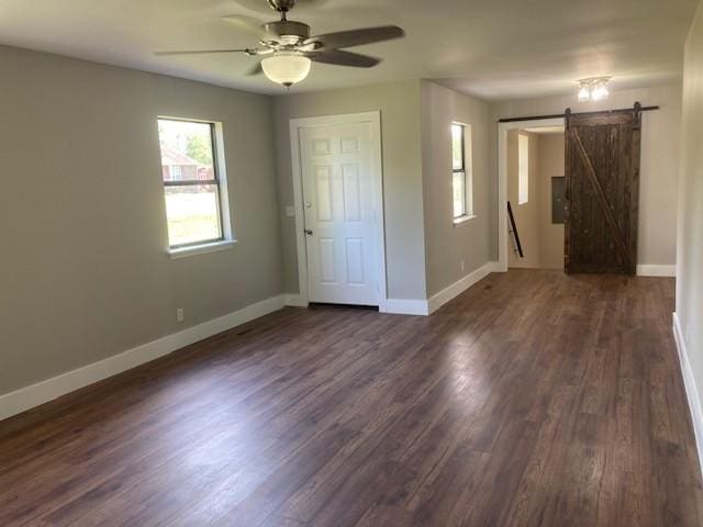 interior space featuring dark wood-type flooring, a barn door, baseboards, and ceiling fan