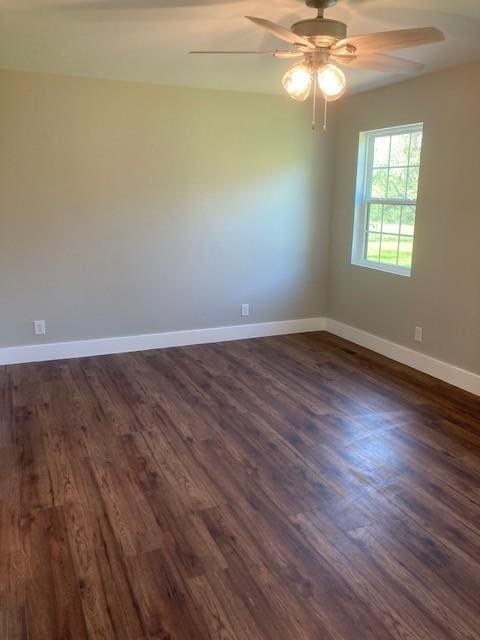 spare room featuring ceiling fan, baseboards, and dark wood-style flooring