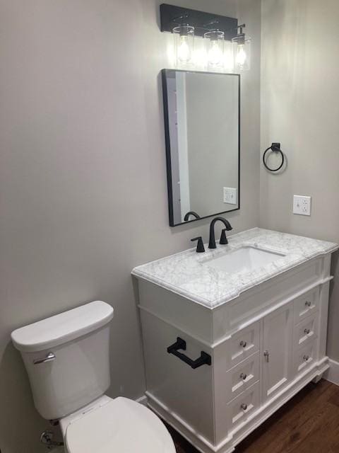 half bath featuring vanity, toilet, and wood finished floors
