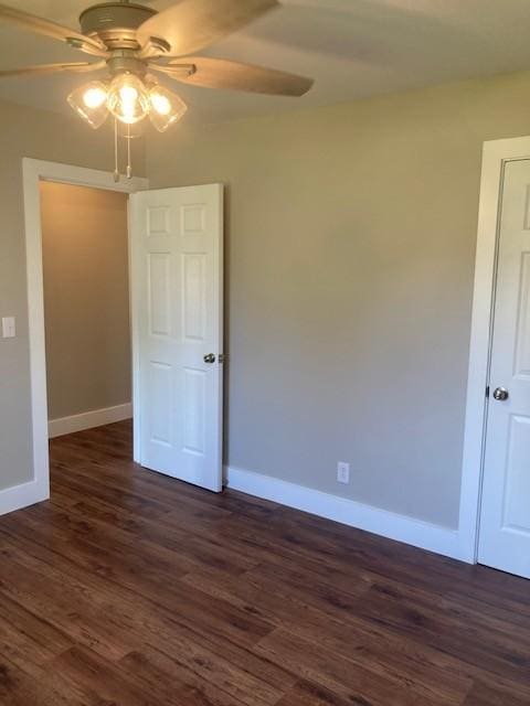 unfurnished room with dark wood-style flooring, ceiling fan, and baseboards
