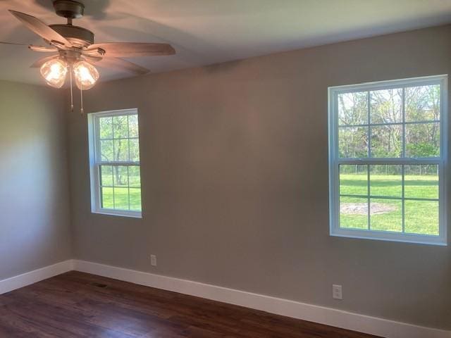 unfurnished room featuring baseboards, ceiling fan, and dark wood-style floors