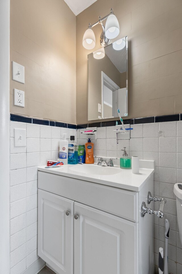 half bathroom with vanity and tile walls