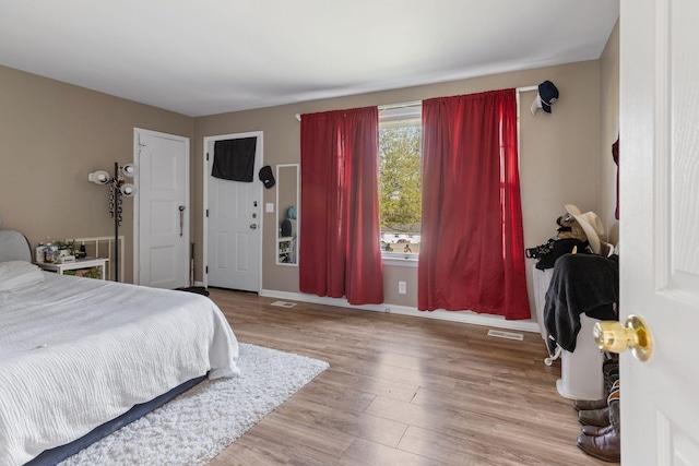 bedroom featuring visible vents, baseboards, and wood finished floors