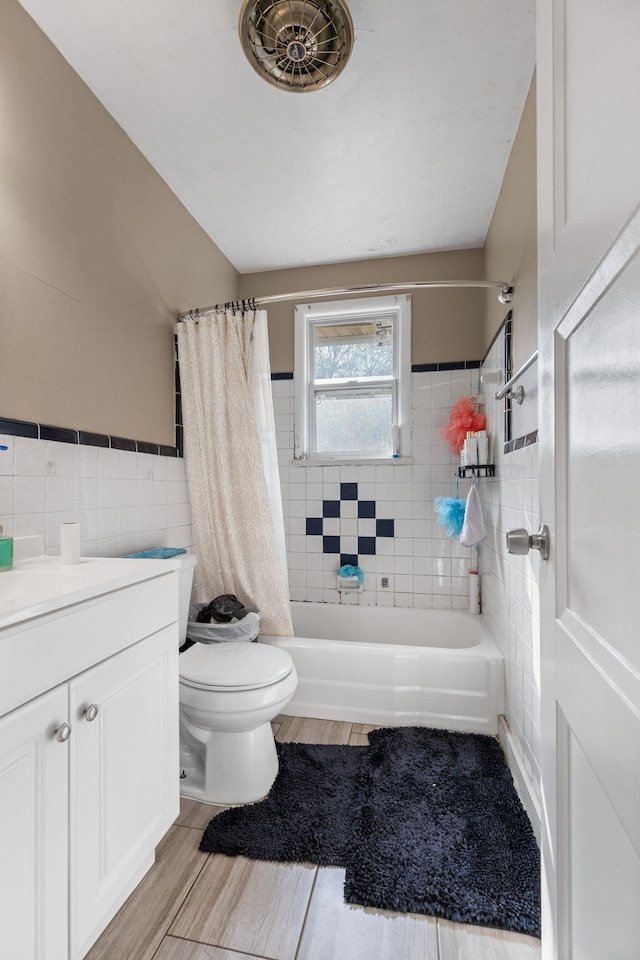 full bath with shower / bath combo, tile walls, toilet, vanity, and wood finished floors