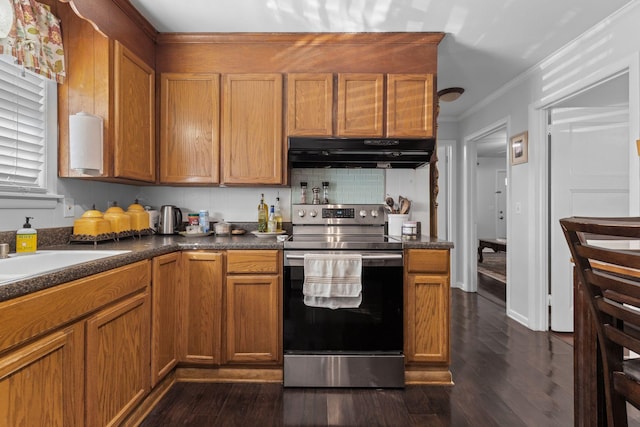 kitchen featuring stainless steel range with electric cooktop, dark wood finished floors, brown cabinetry, under cabinet range hood, and dark countertops