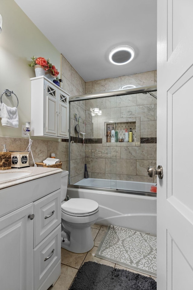 full bathroom with toilet, tile patterned floors, vanity, and combined bath / shower with glass door