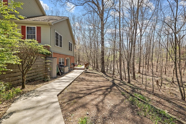 view of property exterior featuring brick siding and a shingled roof