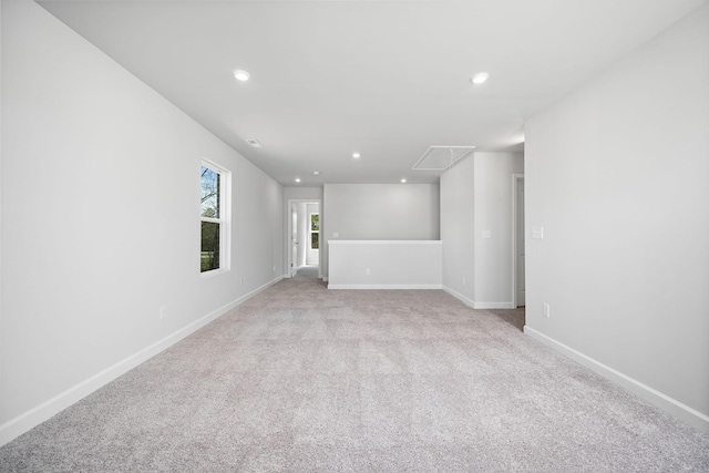 spare room with visible vents, baseboards, recessed lighting, attic access, and light carpet