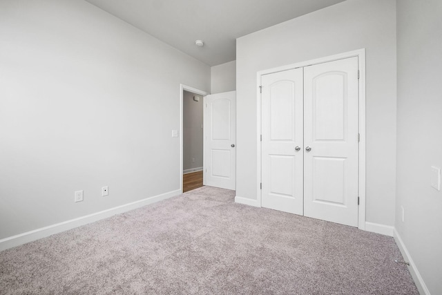 unfurnished bedroom with carpet floors, baseboards, and a closet