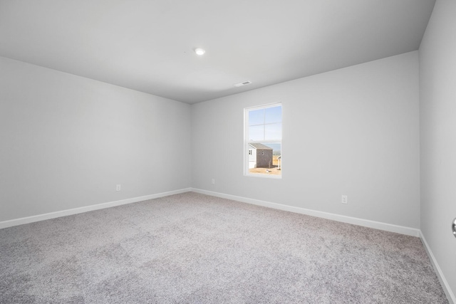 carpeted empty room with baseboards, visible vents, and recessed lighting