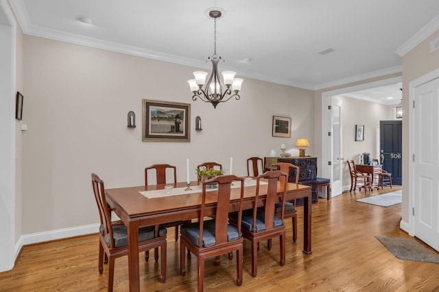 dining room with crown molding, light wood-style flooring, a notable chandelier, and baseboards